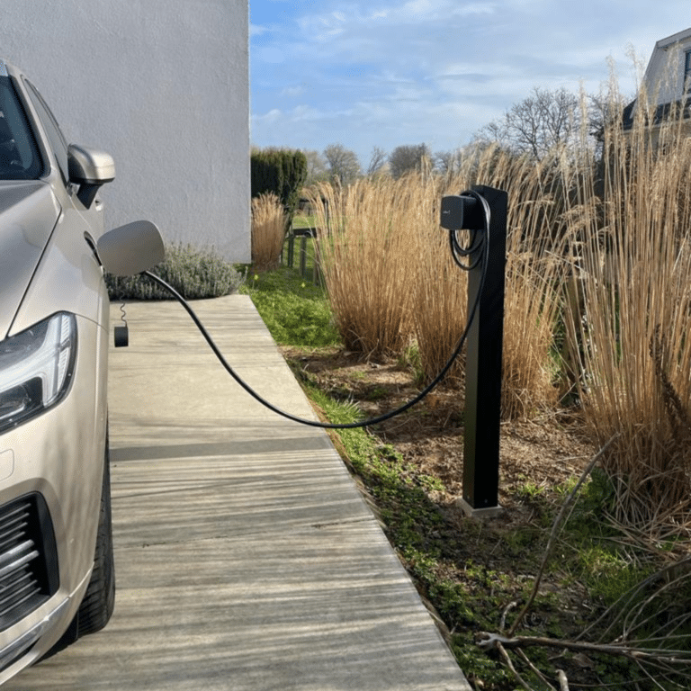 Zwarte laadpaal installatie Wallbox op paal in tuin. Volvo laadt op