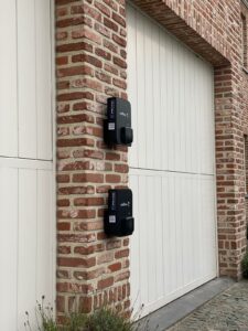 Twee zwarte laadpalen installatie Wallbox aan buitengevel van garages thuis.
