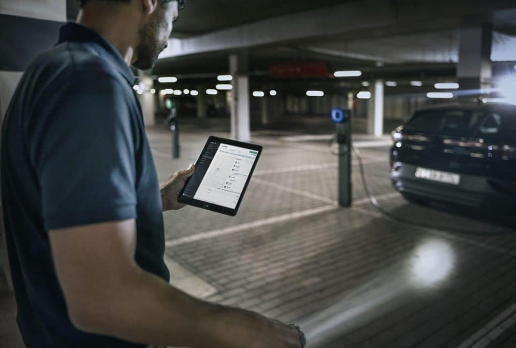 Man zoekt via een app op tablet een beschikbare laadpaal in een ondergrondse parking.
