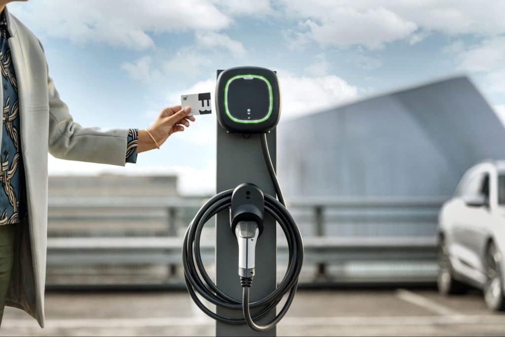 EV-rijder houdt een laadpas tegen een openbare Wallbox laadpaal om de laadsessie te starten.
