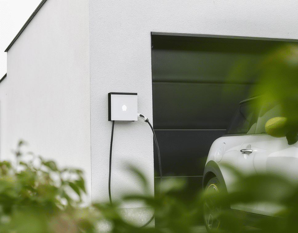 Slimme laadpaal aan de gevel die een elektrische wagen oplaadt voor de garage.