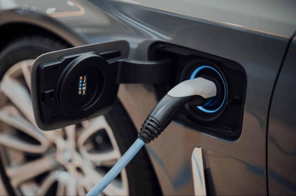 Laadstekker aangesloten op een elektrische wagen die oplaadt aan een laadpaal.