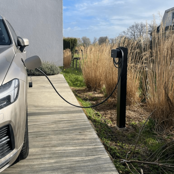 Zwarte laadpaal installatie Wallbox op paal in tuin. Volvo laadt op