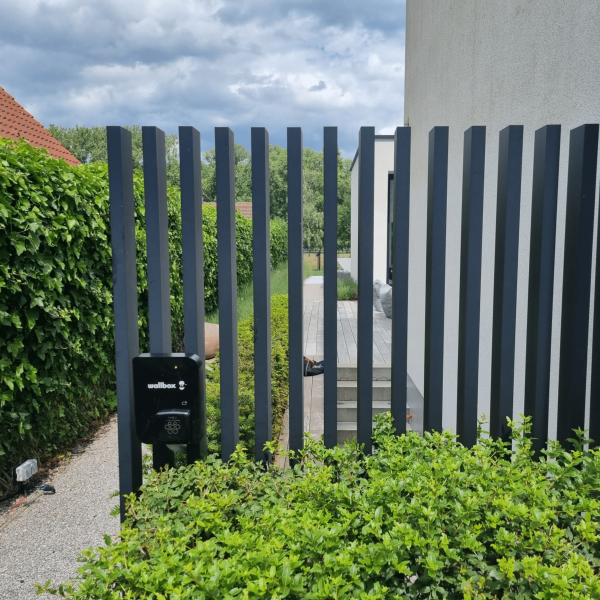 Zwarte laadpaal installatie Wallbox aan omheining tuin