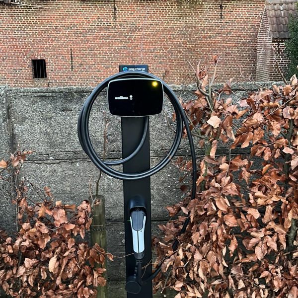 Zwarte laadpaal installatie Wallbox op paal in voortuin thuis.