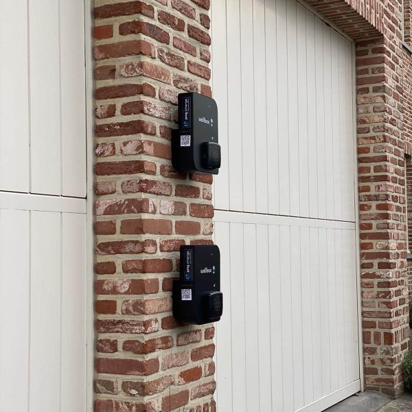 Twee zwarte laadpalen installatie Wallbox aan buitengevel van garages thuis.