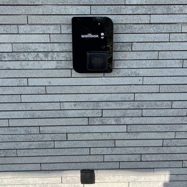 Zwarte laadpaal installatie Wallbox Copper SB - wandmontage buiten grijze gevel